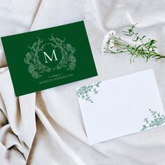 an envelope with a monogrammed letter on it next to a notepad and flowers