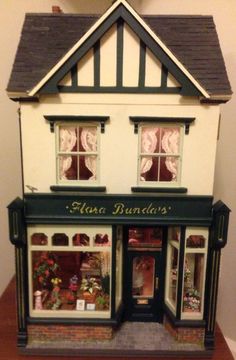 a doll house is shown with the front door open and windows decorated in green trim