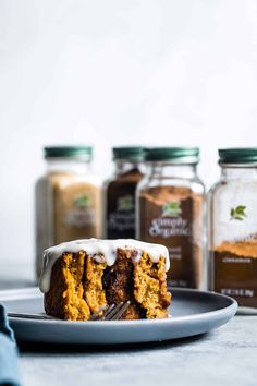 a piece of cake sitting on top of a plate next to jars of coffee and spices