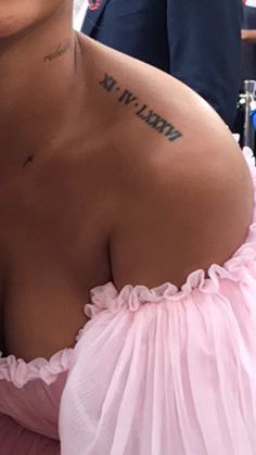 a woman wearing a pink dress with tattoos on her chest