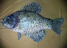 a fish that is sitting on top of a cloth covered tablecloth, with spots all over it