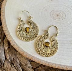 Embrace the bold allure of our Handcrafted Tribal Earrings featuring a striking Tiger's Eye stone at the center. Meticulously crafted with artisanal precision, these earrings seamlessly blend tribal aesthetics with the grounding energy of Tiger's Eye. Make a statement with this unique accessory that exudes strength, style, and a touch of mystique. Material: High quality brass. Width: Approx 1 1/2 inches (3.81 cm) Length: Approx 2 inches (5.08cm) 🔶🐅 **Key Features - **Artisanal Craftsmanship Each pair is thoughtfully handcrafted, ensuring a one-of-a-kind creation. - **Tiger's Eye Centerpiece The captivating Tiger's Eye stone at the center symbolizes strength, protection, and grounding energy. - **Tribal Aesthetics Intricate brass designs draw inspiration from tribal motifs, adding cultura Hippie Brass Jewelry For Festivals, Bohemian Gemstone Jewelry For Festivals, Bohemian Brown Pierced Hoop Earrings, Bohemian Teardrop Brass Hoop Earrings, Bohemian Brown Jewelry For Festivals, Brown Bohemian Festival Jewelry, Bohemian Bronze Hoop Earrings, Bohemian Brass Earrings With Gemstone, Bohemian Brass Gemstone Earrings