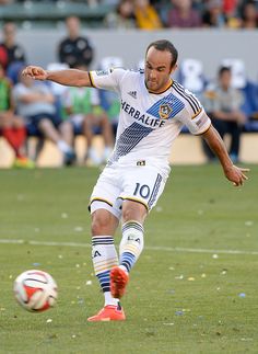 a man kicking a soccer ball on top of a field