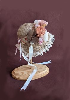 a small hat with flowers on it sitting on top of a wooden stand