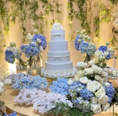 a wedding cake surrounded by blue and white flowers