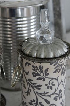 an ornate canister sits next to two silver cans