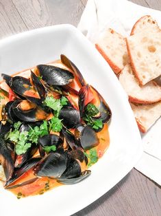 a white plate topped with mussels and bread