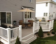 a deck with chairs and an umbrella next to a house