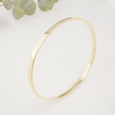 "Introducing our exquisite Solid 14K Gold Bangle, meticulously forged into a flawless round shape, this bangle epitomizes the artistry of skilled goldsmiths. Crafted from solid 14k gold, its solid construction ensures enduring beauty and resilience. Its robust 3mm width and 1.5mm thickness distinguishes it from more delicate alternatives. The lustrous surface reflects the unparalleled quality of the material, making it a luxurious addition to any jewelry collection. Each bangle will be made to order for you. Please enter your hand circumference. Bangle width: 3mm Bangle thickess: 1.5mm Bangle inside diameter: 6.5mm(2.5\") -measuring 19cm size" Flexible Yellow Gold Round Cuff Bracelet, Flexible Gold Cuff Bracelet, Flexible Yellow Gold Cuff Bracelet, Timeless Yellow Gold Round Cuff Bracelet, Timeless Yellow Gold Cuff Bracelet, Modern Flexible Round Bangle, Modern Round Cuff Bracelet For Wedding, Timeless Gold Bangle Bracelet With Polished Finish, Gold Bracelets With Smooth Bezel