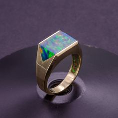 Make a statement with this stunning solid gold signet ring, featuring a large lab-made black opal inlay that shimmers with a captivating iridescence. The inlay is expertly crafted and set into the gold with precision, resulting in a bold and unique design that's sure to turn heads. Unlike cheap hollow or plated rings, this signet ring is crafted from solid gold throughout for a luxurious and high-quality finish that's built to last. Perfect for men who appreciate fine jewelry and bold design, th Opal Rings With Polished Finish For Formal Occasions, Modern Gold Opal Rings, Formal Opal Rings With Polished Finish, Modern Formal Opal Jewelry, Modern 14k Gold Opal Ring With Polished Finish, Formal Opal Ring With Polished Finish, Modern Opal Ring In 14k Gold With Polished Finish, Modern 14k Gold Opal Ring For Formal Events, Modern 14k Gold Opal Ring For Formal Occasions