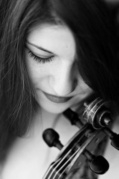 a woman is playing the violin with her eyes closed