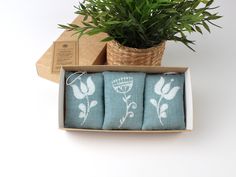 three tea towels in a box next to a potted plant