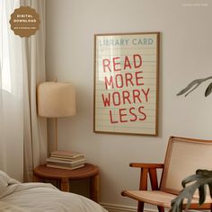 a bedroom with a bed, chair and poster on the wall above it that reads library card read more worry less