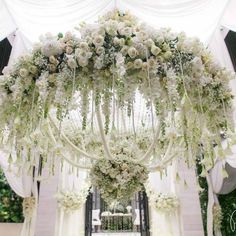 a wedding ceremony with white flowers hanging from the ceiling