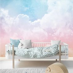 a child's bedroom with pink and blue clouds painted on the wall behind it