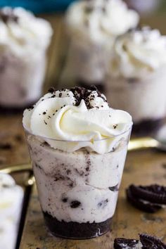 there is a dessert in the glass with whipped cream and cookies around it on the table