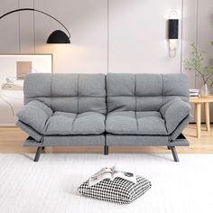 a grey couch sitting on top of a white rug