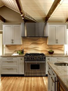 a kitchen with white cabinets and stainless steel stove top oven in the center of the room