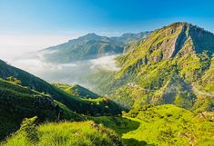 the mountains are covered in clouds and grass