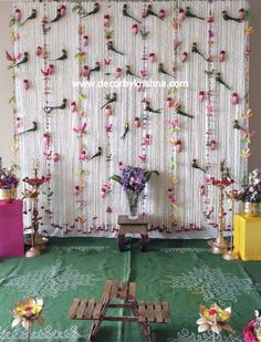 a green table cloth with flowers on it and some candles in front of the curtain