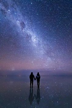 two people holding hands in front of the night sky with stars above them and an image of