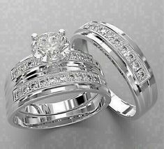 two white gold wedding rings with diamonds on each one and an engagement ring in the middle