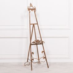 an ornately decorated metal easel stands against a white wall