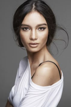 a woman with dark hair wearing a white top