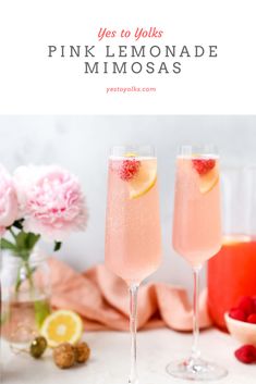 two glasses filled with pink lemonade and raspberries on top of a table