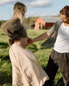 two people standing in the grass touching hands