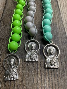 "Teach your child about the principles of sacrifice and help them keep track of their good deeds with these Colorful Saint Therese Sacrifice Beads (also known as Good Deed beads) featuring a silver Saint Benedict Flared Edge Crucifix and coordinating silver Saint Therese Medal. Catholic Sacrifice Beads consist of ten beads, which can be pulled and remain in place, to count the acts of love or sacrifices a person makes in a day for God.  Our handmade Saint Therese Sacrifice Beads are made of 10mm Handmade Green Spiritual Rosary Bracelet, Adjustable Rosary With Large Beads As Gift, Adjustable Large Beads Rosary As Gift, Blessing Beaded Rosary Bracelet With Round Beads, Beaded Rosary Bracelet For Blessing, Sacrifice Beads, One Decade Rosary, Saint Therese, Acts Of Love