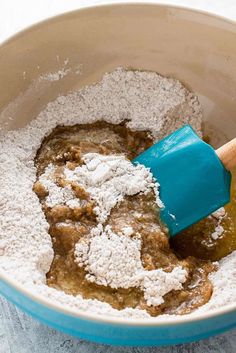 a bowl filled with powdered sugar and an orange spatula on top of it