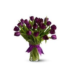 a vase filled with purple tulips on top of a white table next to a pink frame