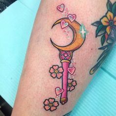 a woman's leg with a tattoo on it and a crescent moon holding a key