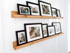 two wooden shelves with pictures on them and one shelf is holding several framed photos in it