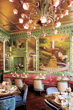 an ornately decorated dining room with pink flowers on the ceiling and green walls, along with blue upholstered chairs