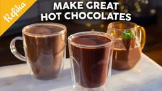 two cups filled with hot chocolate sitting on top of a counter