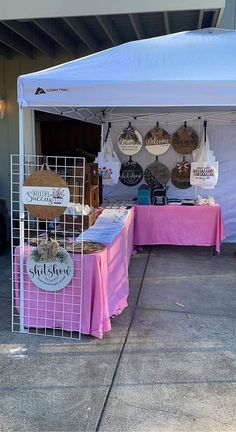 a white tent with pink table cloths and signs on the side of it for sale