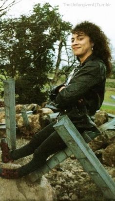 a woman sitting on top of a pile of rocks with her legs crossed in the air