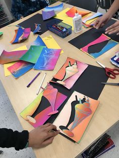 children are making art work with paper and scissors on the table in front of them