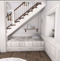 a bed sitting under a stair case next to a wooden floor in a room with white walls