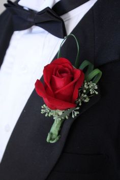 a man in a tuxedo is wearing a boutonniere with a red rose on it