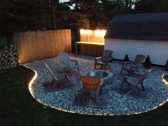 an outdoor fire pit surrounded by chairs and gravel