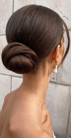 a woman with her back to the camera, wearing a white top and hair in a low bun