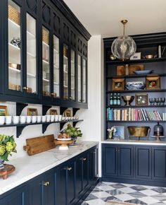 a kitchen with blue cabinets and marble counter tops, white walls, and black flooring