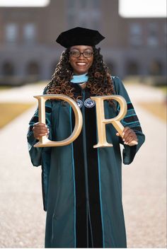 a woman in graduation gown holding the letter dr