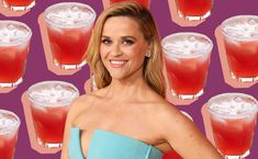 a woman wearing a blue dress standing in front of many glasses of red drinks and smiling