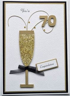 a card with a champagne glass and congratulations written in gold on the front, along with a black ribbon