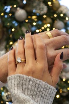 two hands holding each other in front of a christmas tree with lights on the background