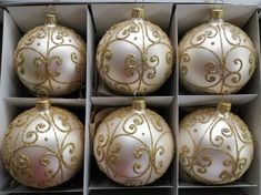 six white and gold ornaments in a box